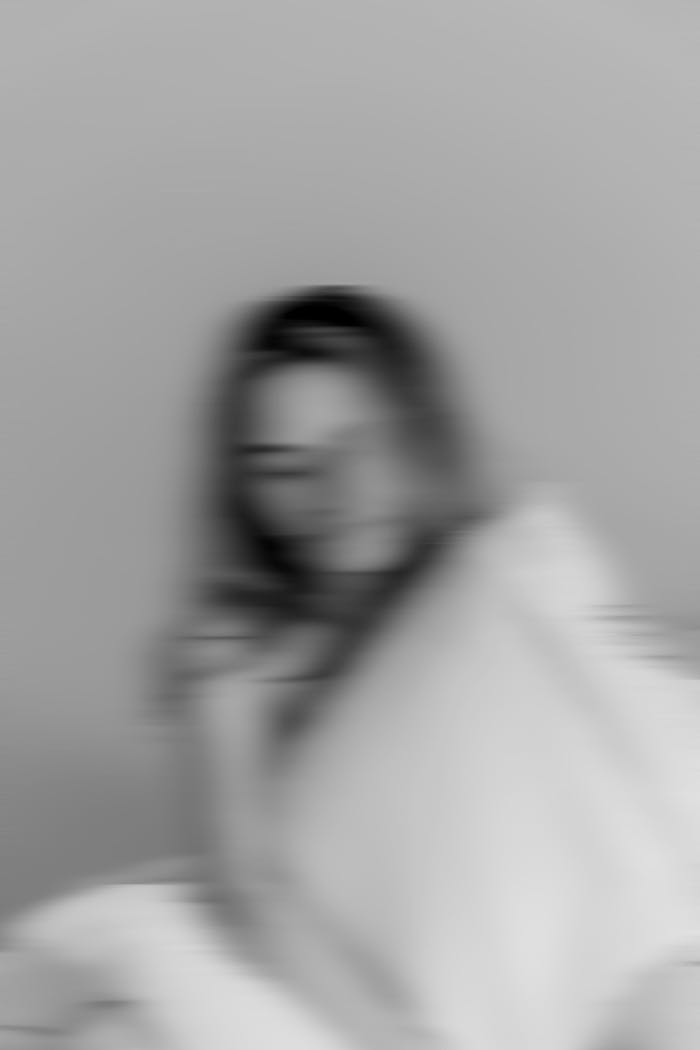 Soft-focus monochrome image of a woman holding a pillow, conveying a dreamy mood.