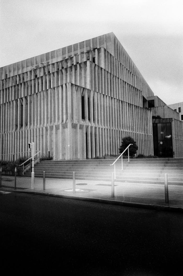 Black and white photo of a modern brutalist building with geometric design and urban scenery.