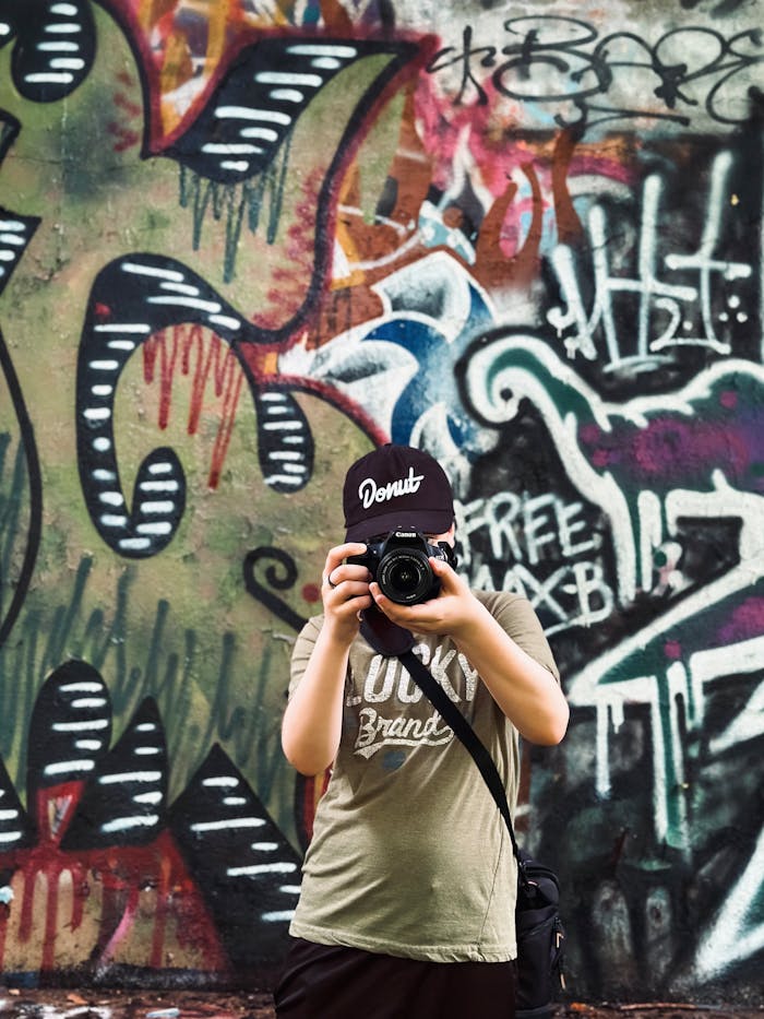 A teenager photographing in front of a vibrant graffiti wall in Washington, DC.